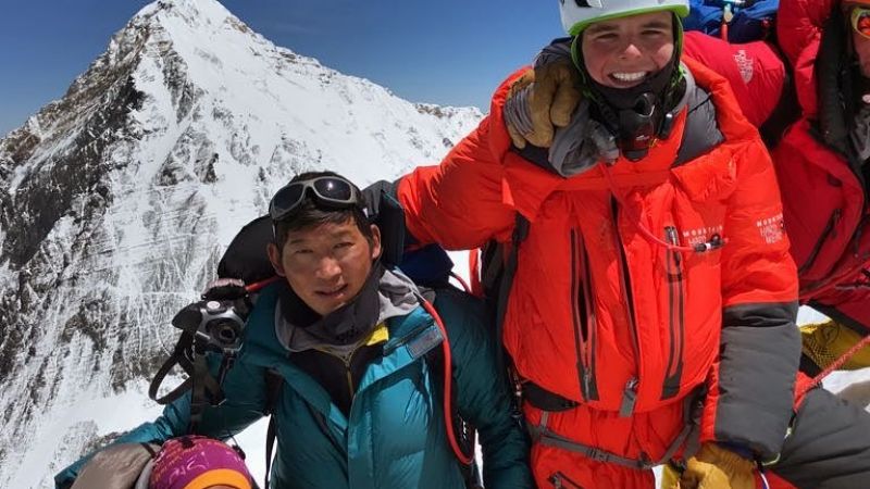 Climbers pose on top of a high mountain summit in the Himalayas.