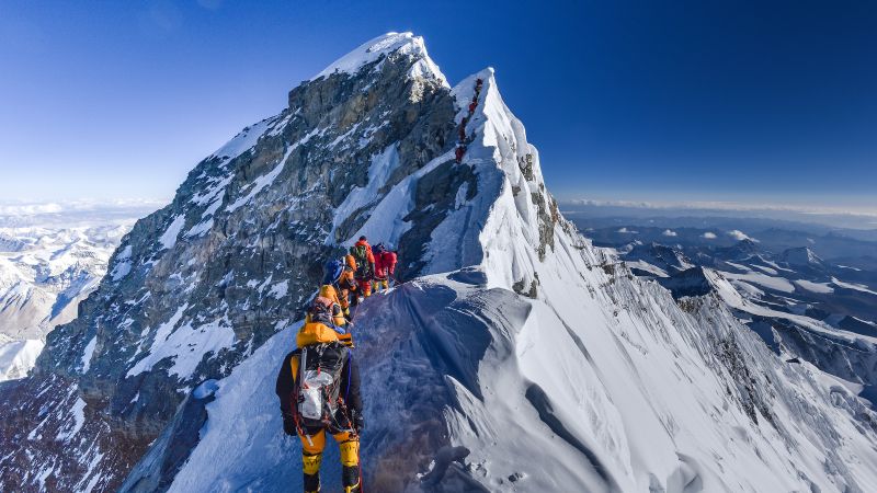 A line of climbers wait to summit Mount Everest.